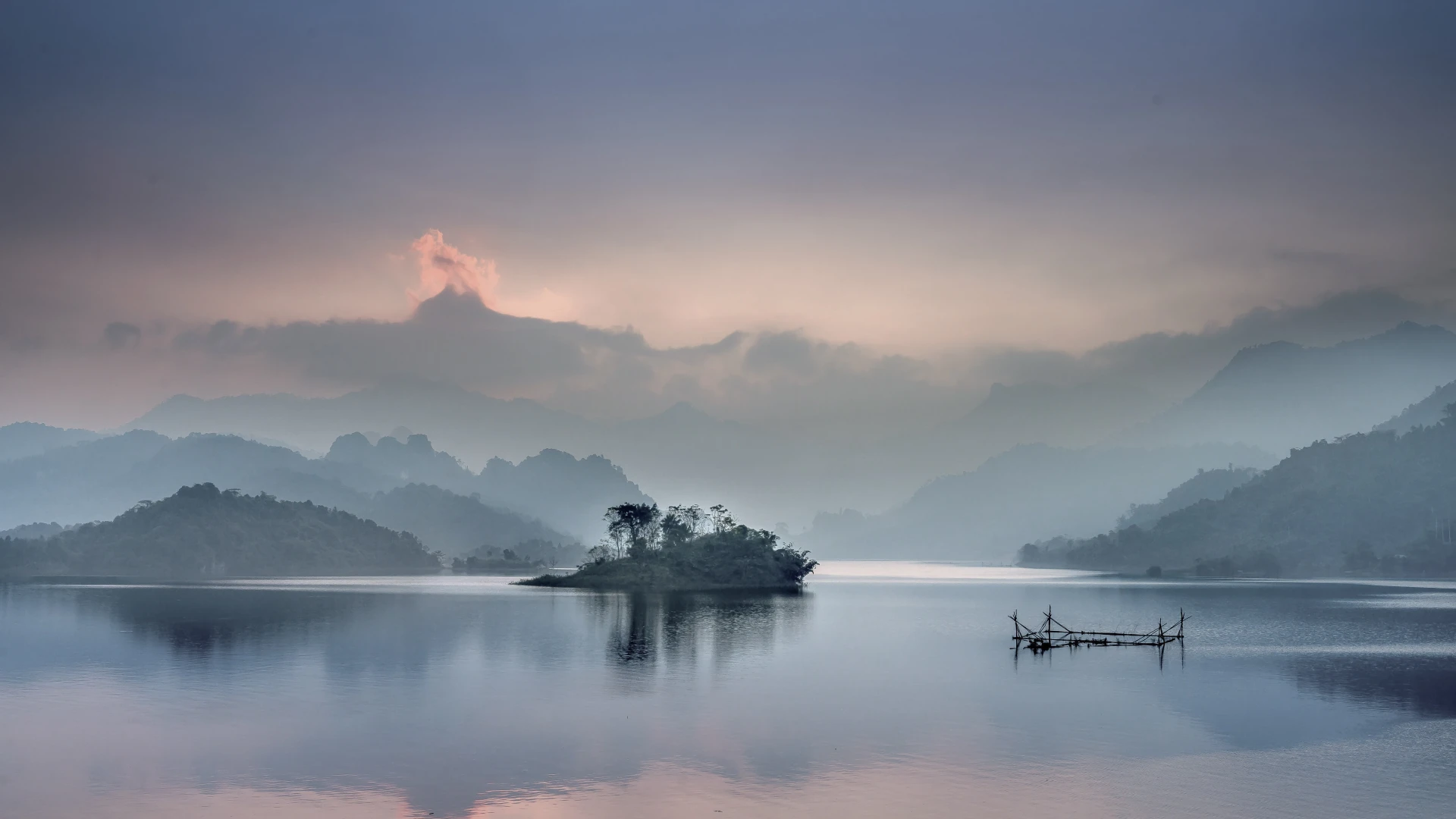 A small working boat crosses Hòa Bình Lake as evening light fades.