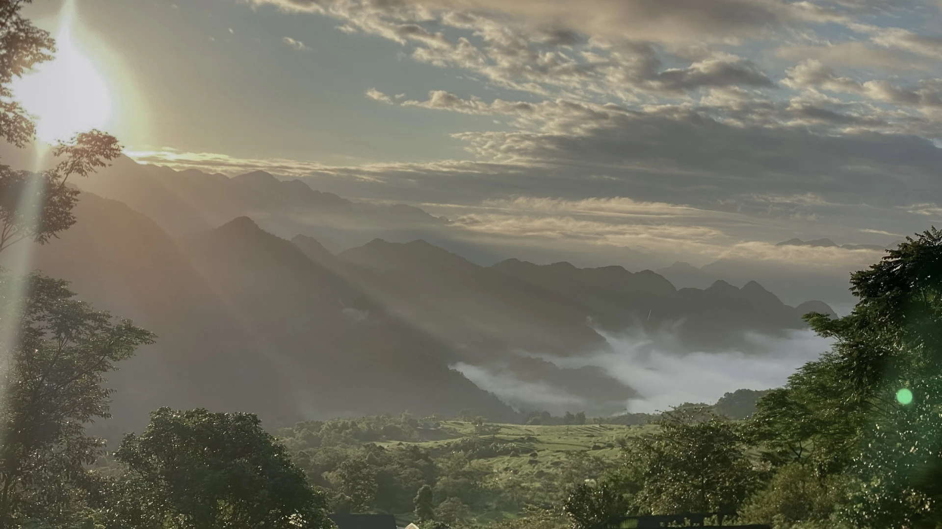 Morning light reaches across layered mountains and low cloud