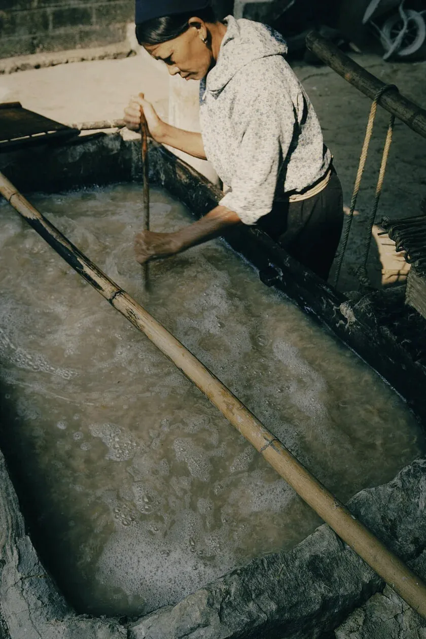 A paper maker working beside a vat of pulp in Dìa Trên.